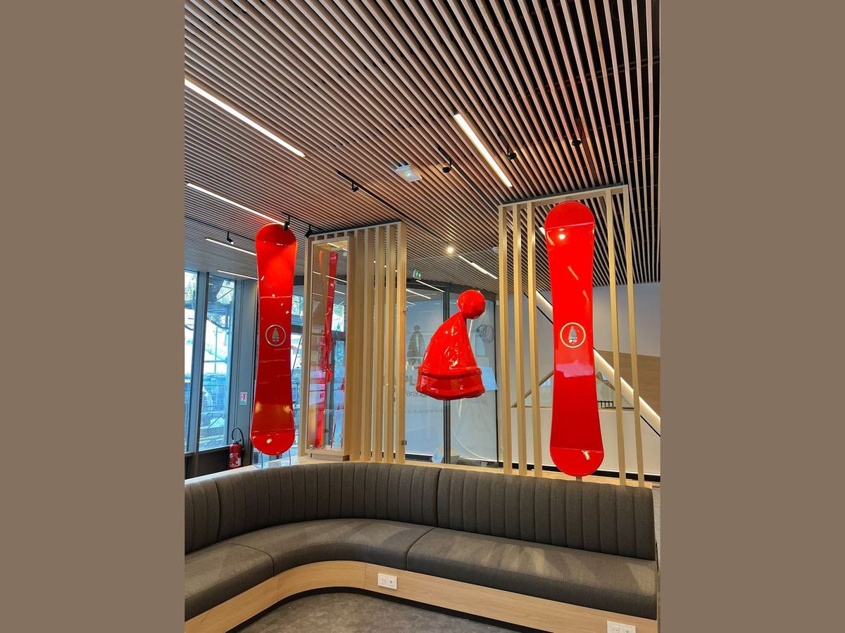 Snowboards et bonnet laqués rouge suspendus dans une station de ski